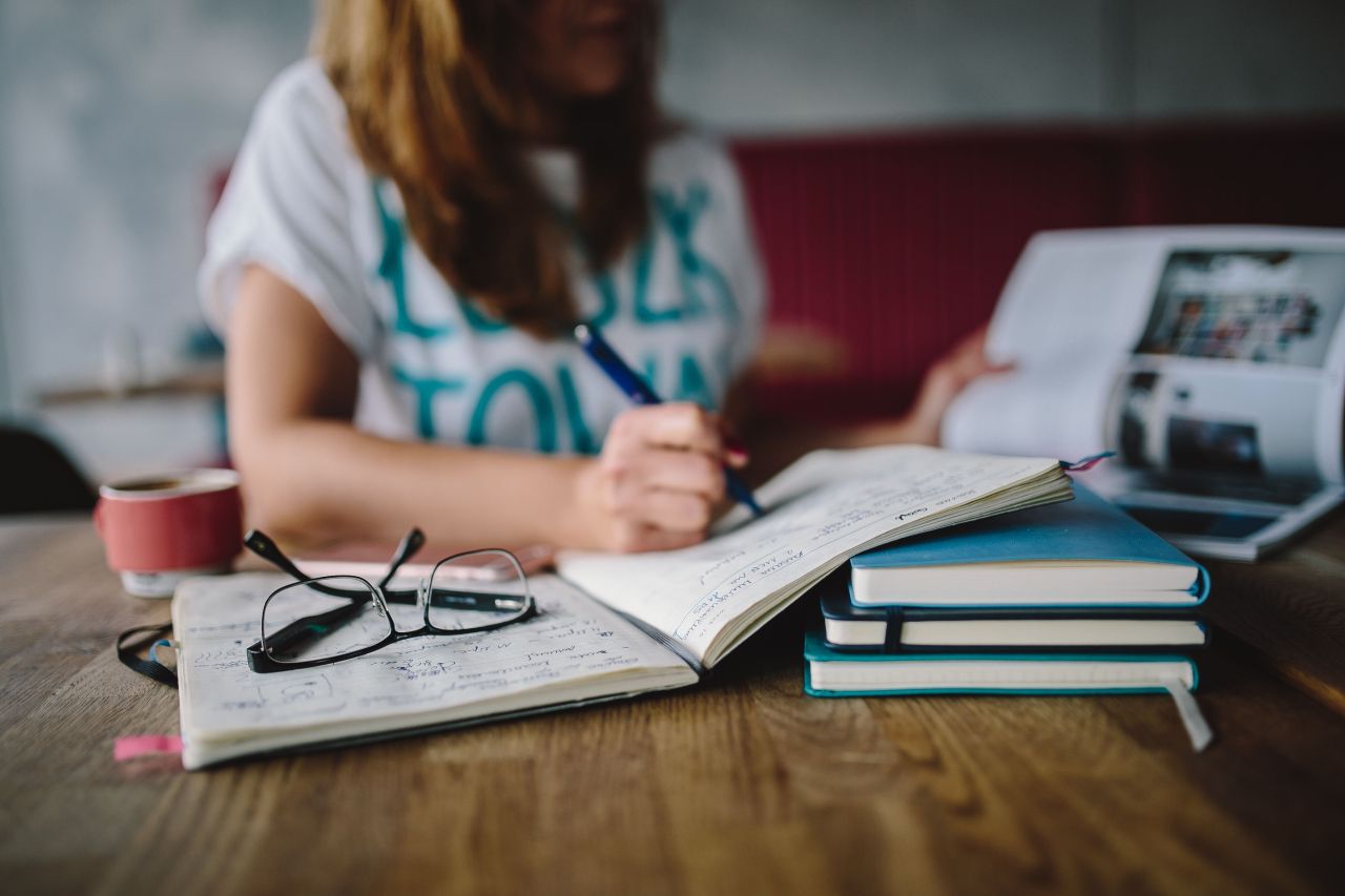 Beautiful blonde woman relaxing with a can of coke on a tree stump by the beach